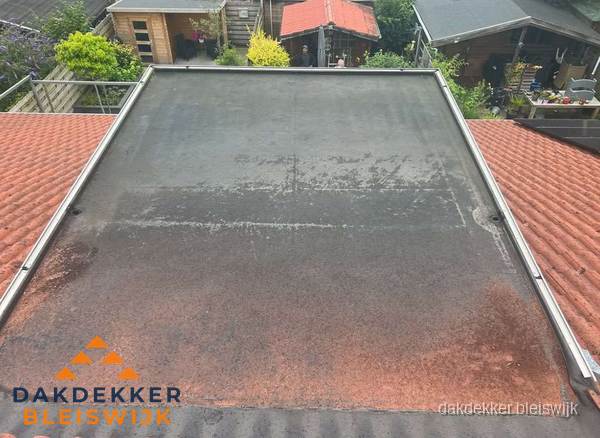 Verouderd plat dak met slijtage tussen schuine daken in Bleiswijk Verouderd plat dak met slijtage tussen schuine daken in Bleiswijk