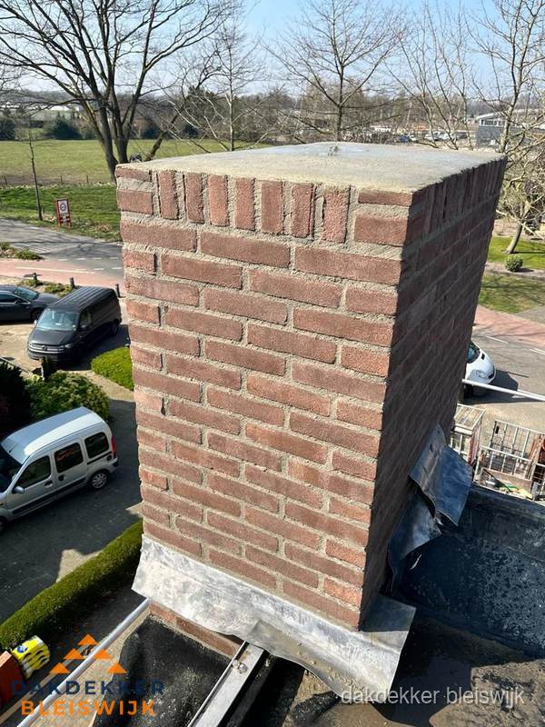 Gemetselde schoorsteen met loodaansluiting op dak in Bleiswijk