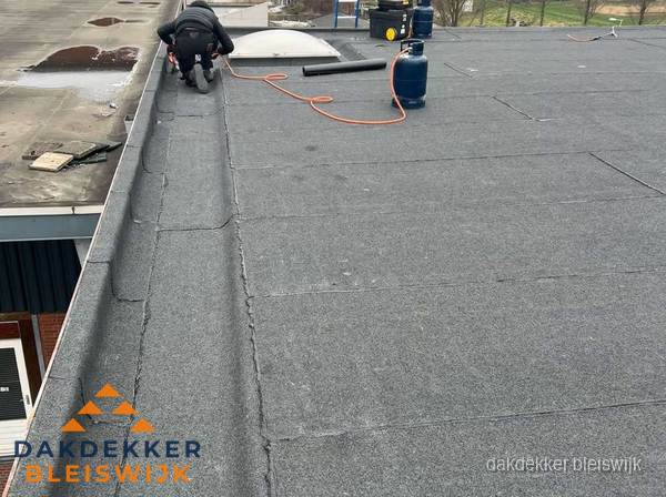 Dakdekker repareert bitumen dakbedekking op groot plat dak in Bleiswijk Dakdekker repareert bitumen dakbedekking op groot plat dak in Bleiswijk