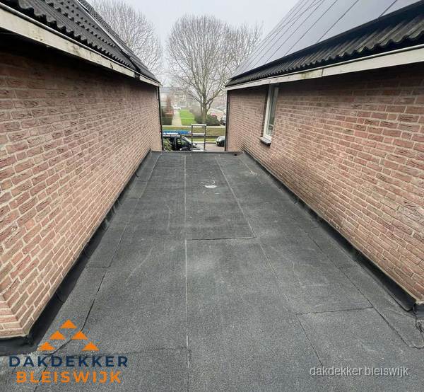 Plat dak met bitumen dakbedekking tussen bakstenen muren in Bleiswijk Plat dak met bitumen dakbedekking tussen bakstenen muren in Bleiswijk